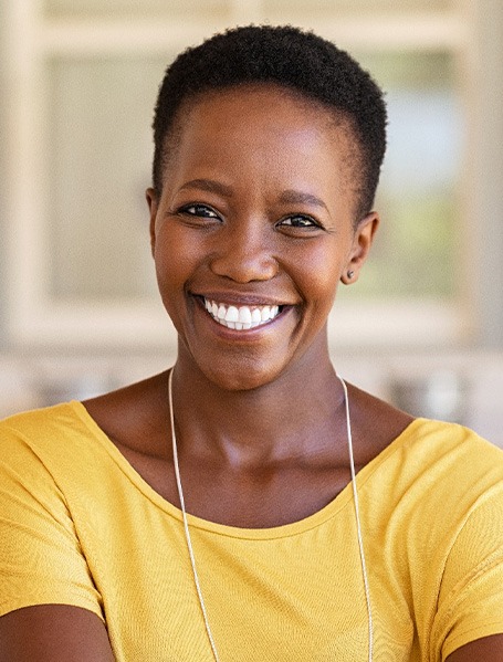 Woman in yellow shirt smiling at home