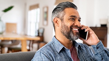 Man smiling while talking on phone at home
