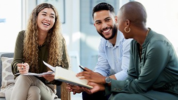 Three working professionals discussing things with notebooks