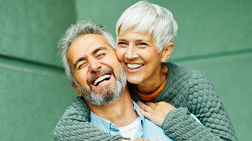 Couple smiling and embracing with a green wall in the background