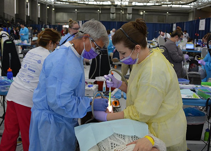 Dentist and dental team member treating patient at volunteer event