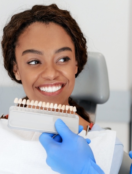 Woman's smile compared with porcelain veneer shade during cosmetic dentistry visit