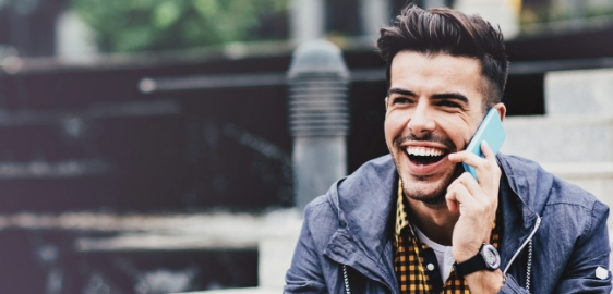 Young man laughing while talking on cell phone outdoors