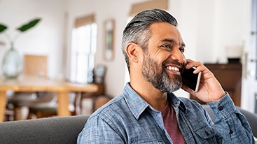 Man smiling while talking on phone at home