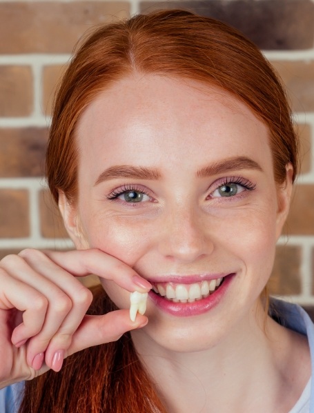 Woman holding tooth after extraction