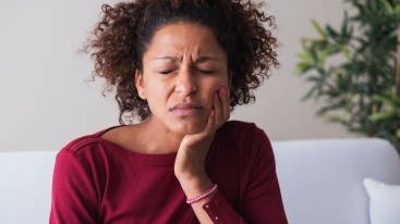 Woman with toothache holding cheek in pain