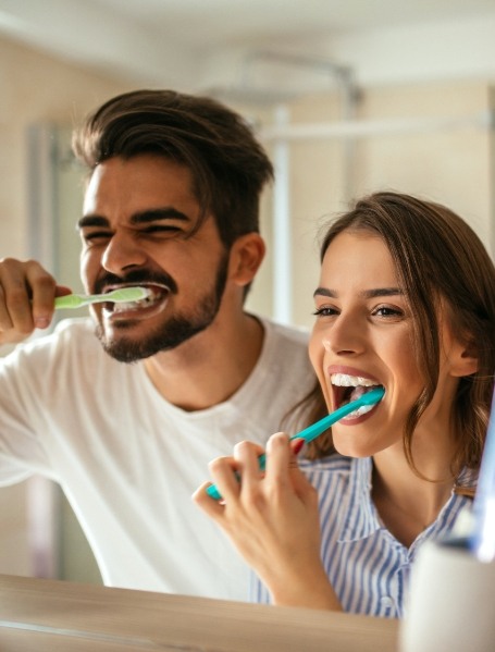 Man and woman brushing theet to prevent dental emergencies