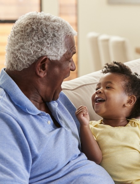 Older man smiling at grandchild enjoying the benefits of dental implants