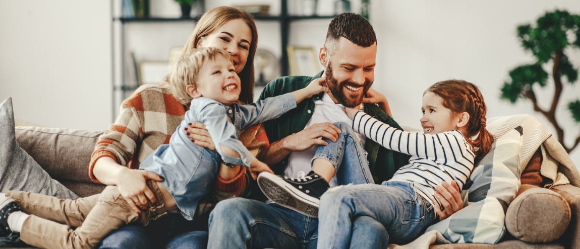 Parents and two young children playing on couch together