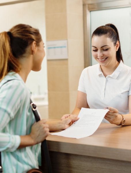 Dental team member and patient reviewing dental insurance forms