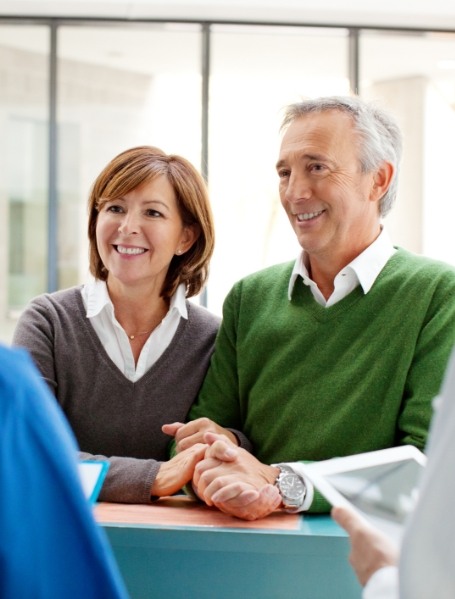 Man and woman checking in at dental office reception desk