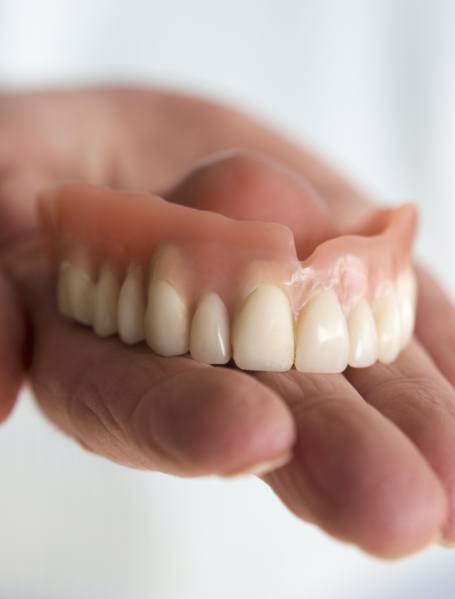 Hand holding a full denture