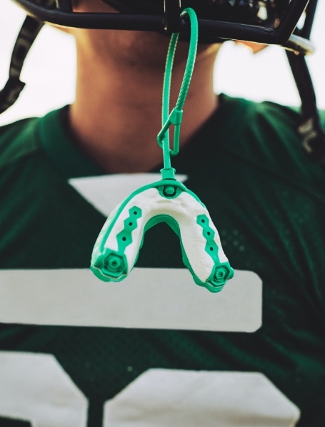 Green sportsguard hanging from football helmet