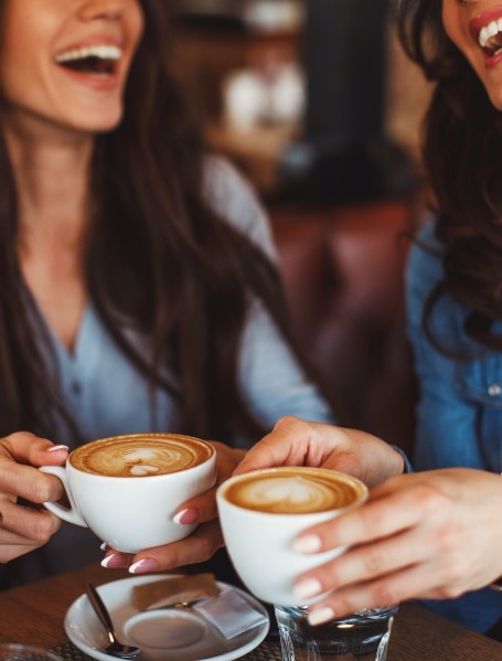Two women drinking coffee which cause tooth discoloration