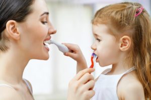 A mother and daughter brushing each other’s teeth.