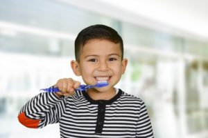 boy smiling while brushing his teeth