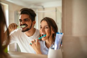 couple brushing their teeth in the mirror