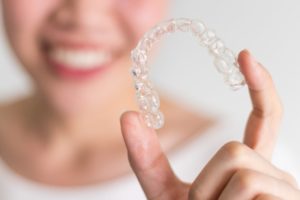 Smiling person holding Invisalign 
