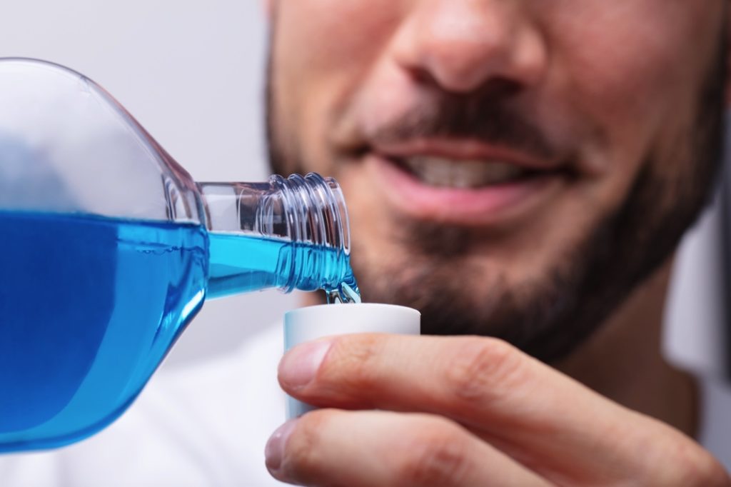 Man using anti-microbial rinse before seeing dentist in Hamden