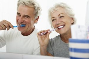 senior man and woman brushing their teeth together 