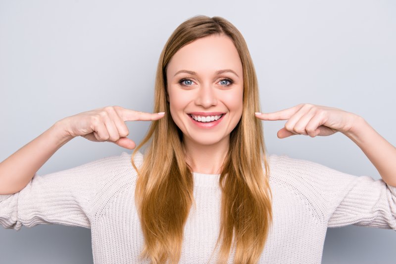 young woman pointing to her smile