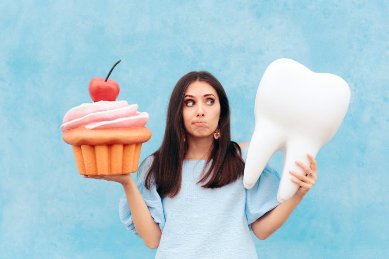Woman holding giant cupcake and giant tooth