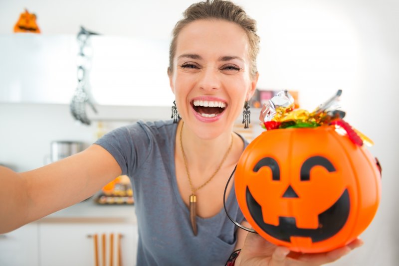 Woman taking a selfie with a halloween bucket full of candy